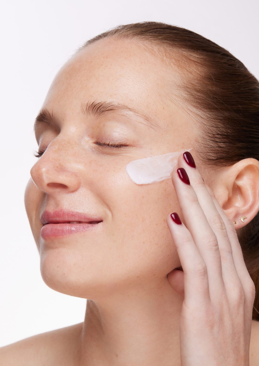 Mujer aplicando crema Skinology en el rostro